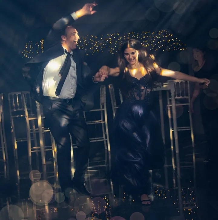 Pareja bailando en la pista entre luces cálidas