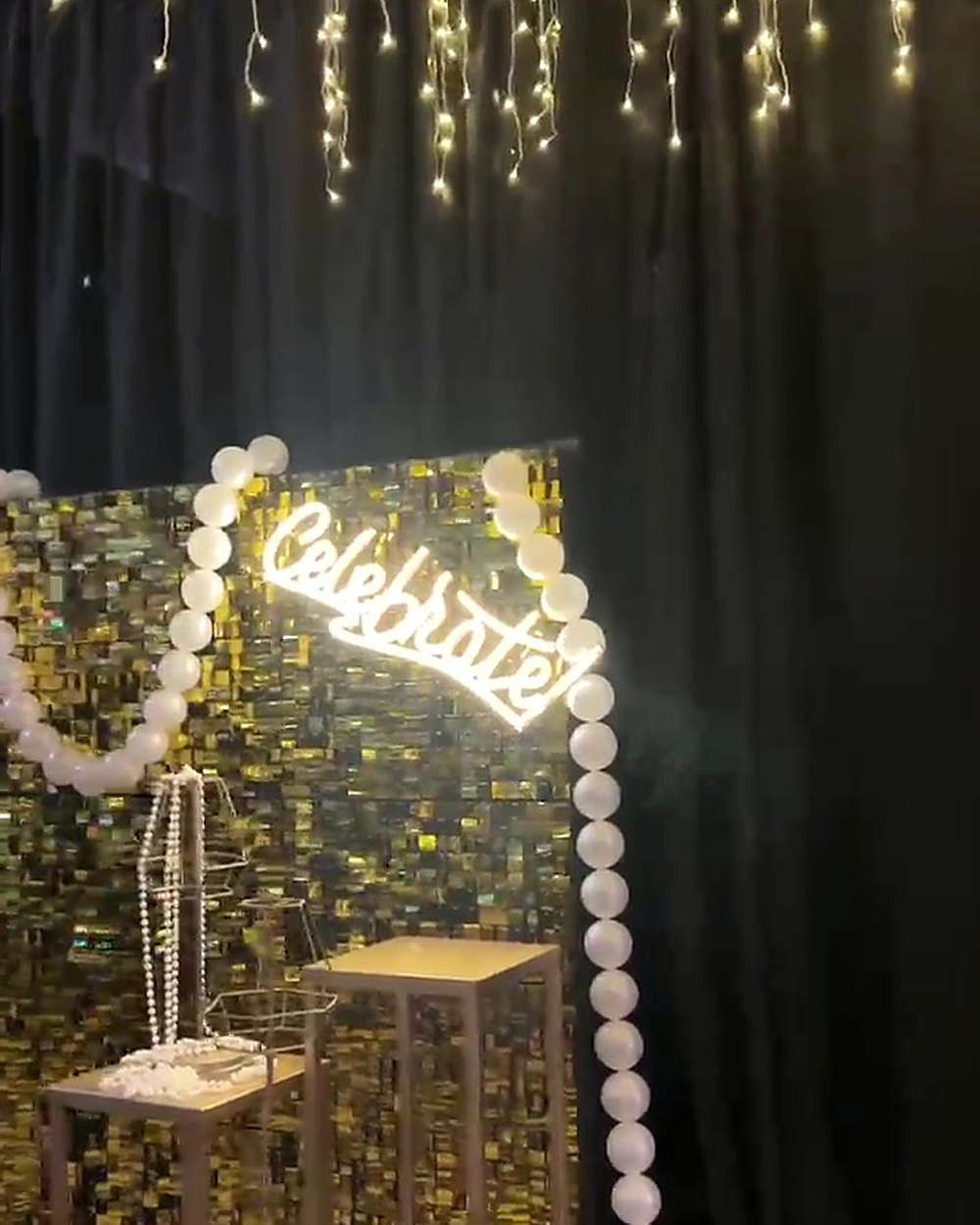 Pared de lentejuelas doradas con cartel de neón y cortina de luces en el Salón Recepción